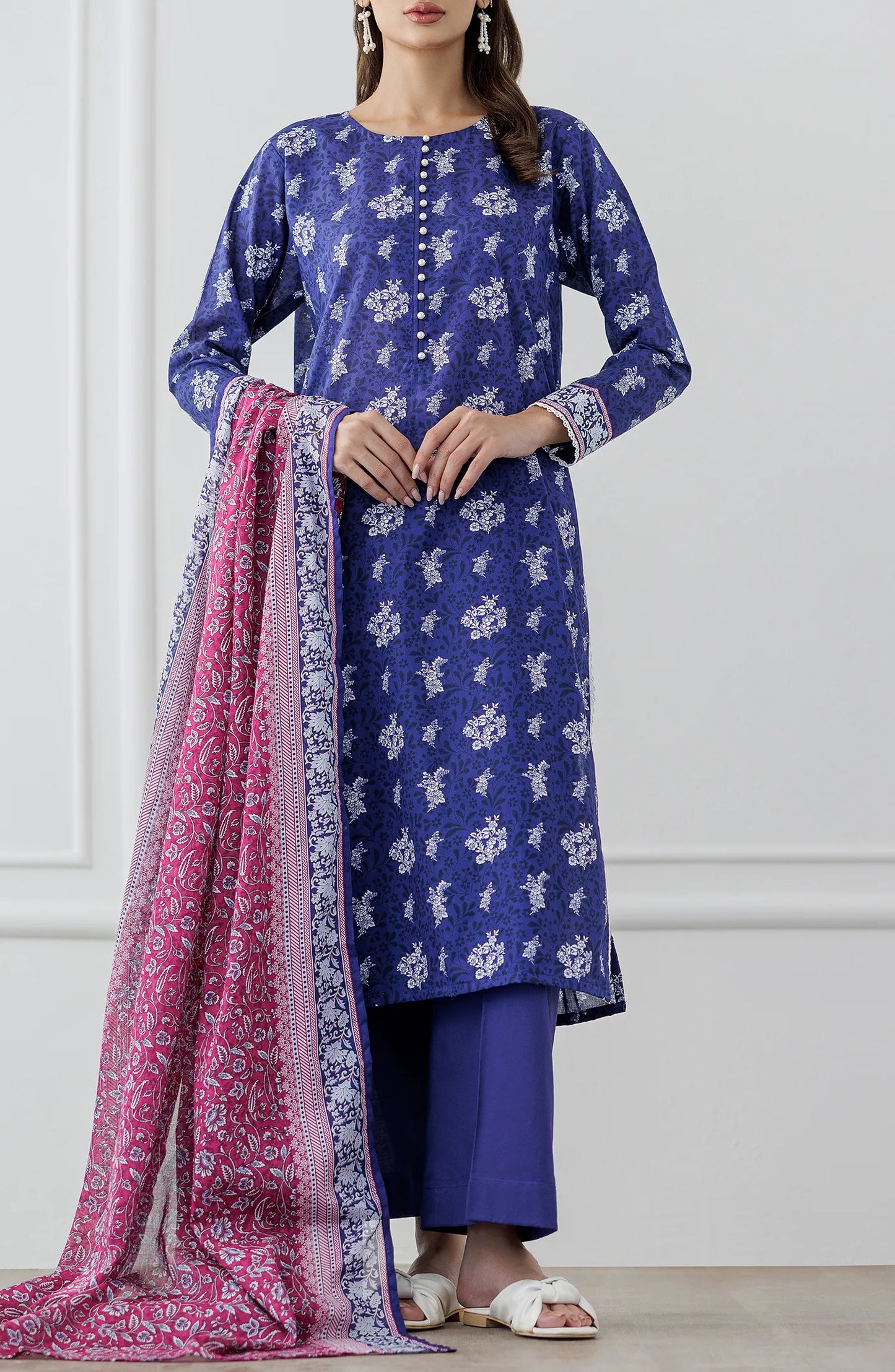 Woman wearing a blue floral dress with a pink dupatta against a plain trouser. Stitched Printed Lawn Shirt Dupatta & Pant - 3 Piece Suits - OTL-25-476
