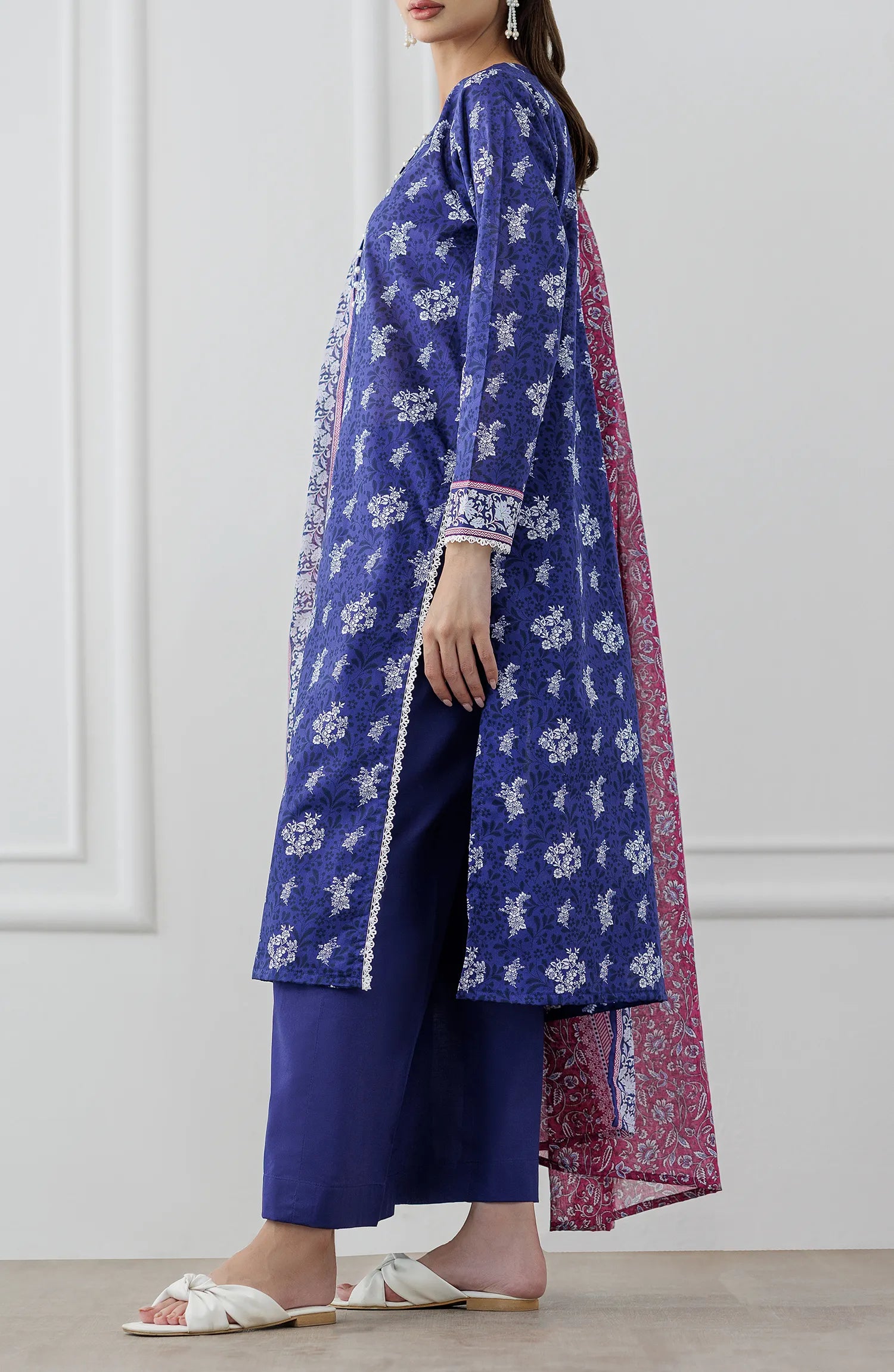 Woman wearing a blue floral dress with a pink dupatta against a plain trouser. Stitched Printed Lawn Shirt Dupatta & Pant - 3 Piece Suits - OTL-25-476