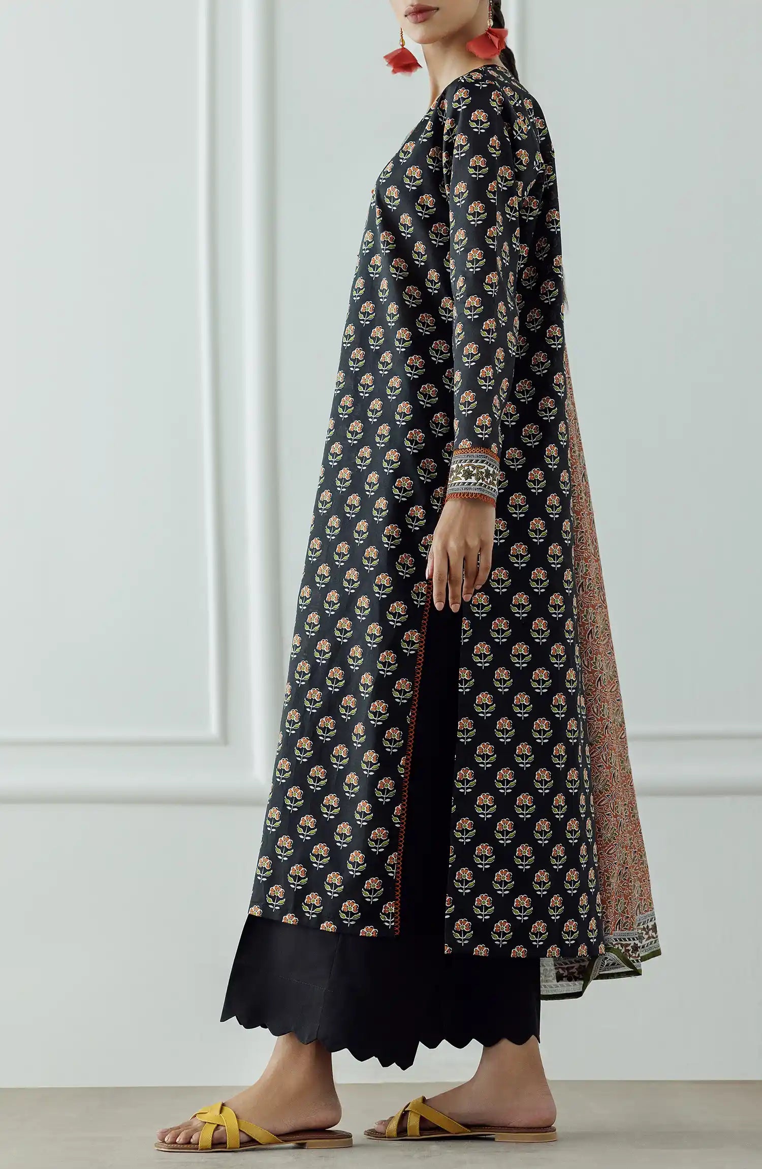 Woman wearing a black patterned kurta with a long dupatta against a black trouser. Stitched Printed Lawn Shirt Dupatta & Pant - 3 Piece - OTL-25-004.