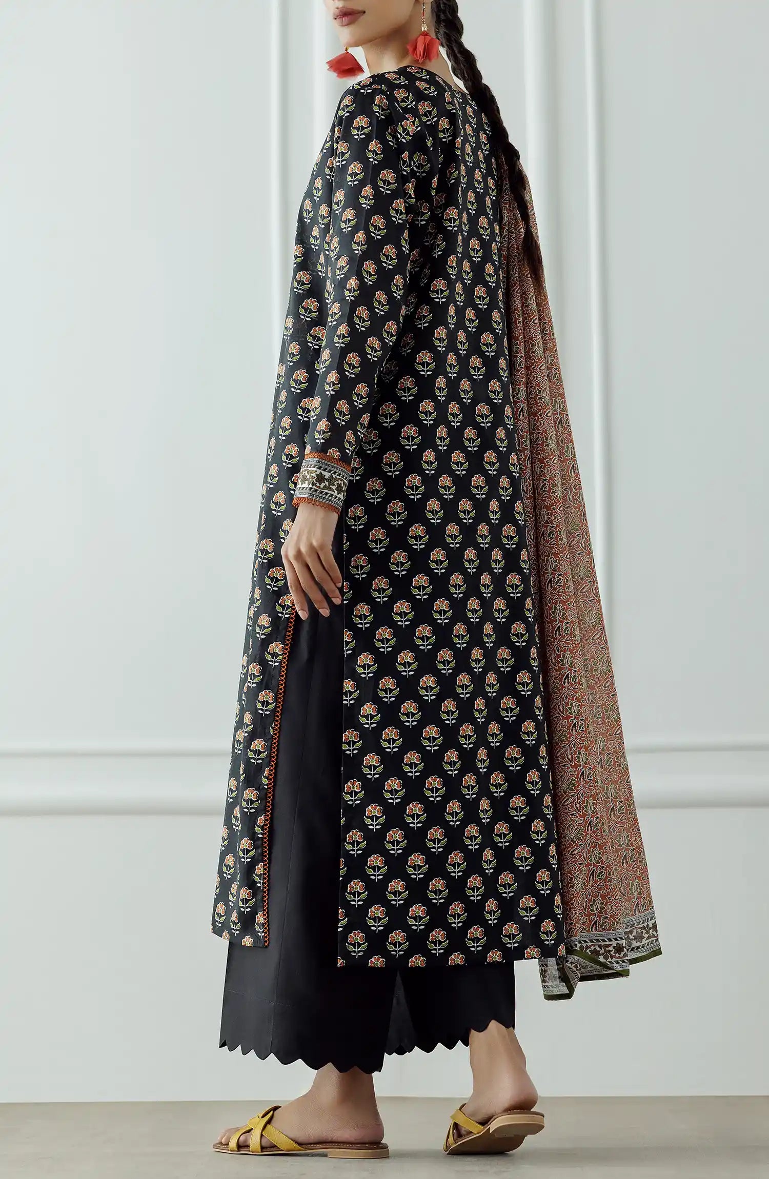 Woman wearing a black patterned kurta with a long dupatta against a black plain shalwar. UNSTITCHED Printed Lawn Shirt Dupatta & Pant - 3 Piece - OTL-25-004