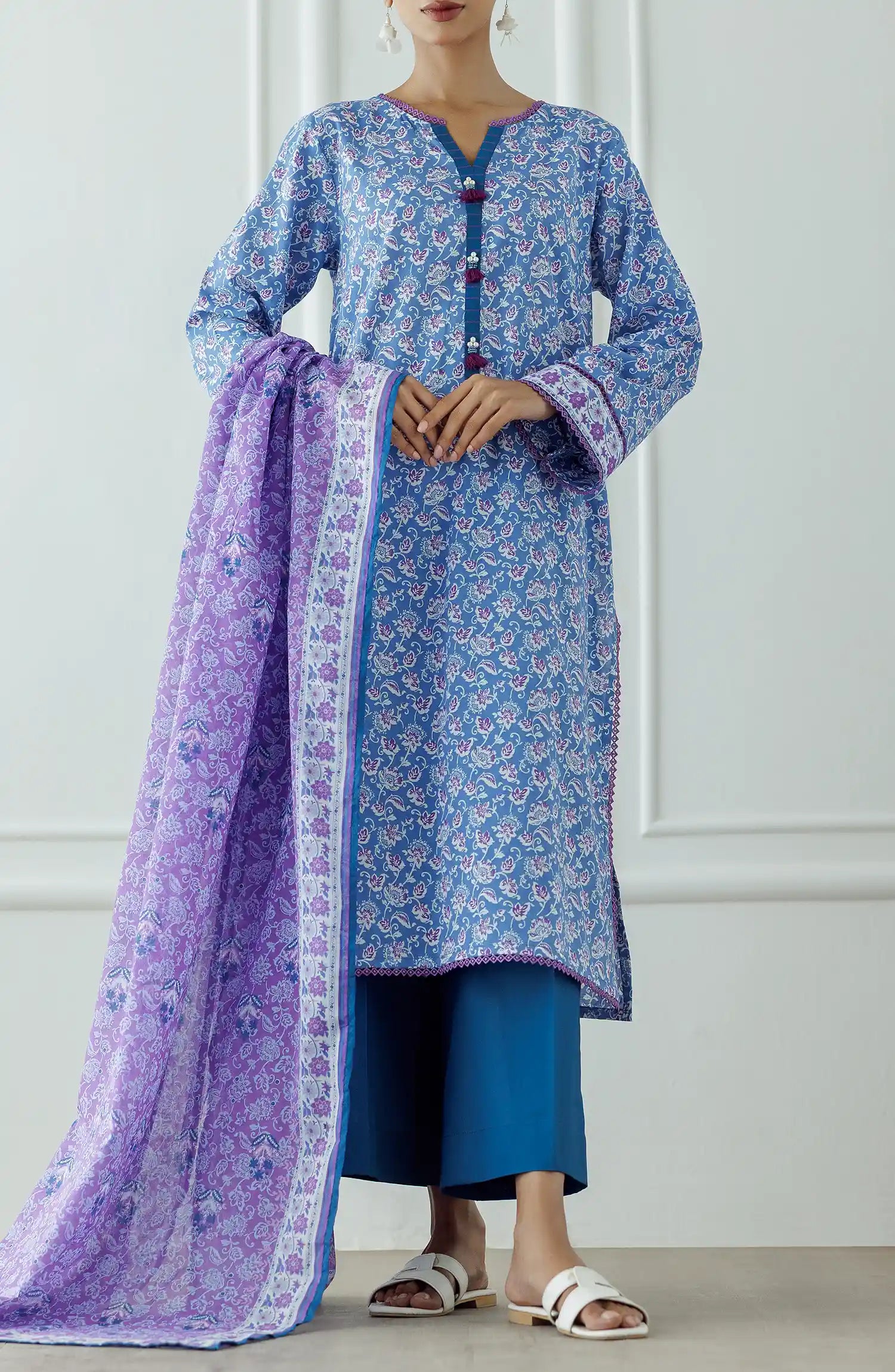 Woman wearing a blue floral kurta with a matching dupatta and blue pants against a plain trouser. Stitched Printed Lawn Shirt Dupatta & Pant - 3 Piece Suits - OTL-25-043