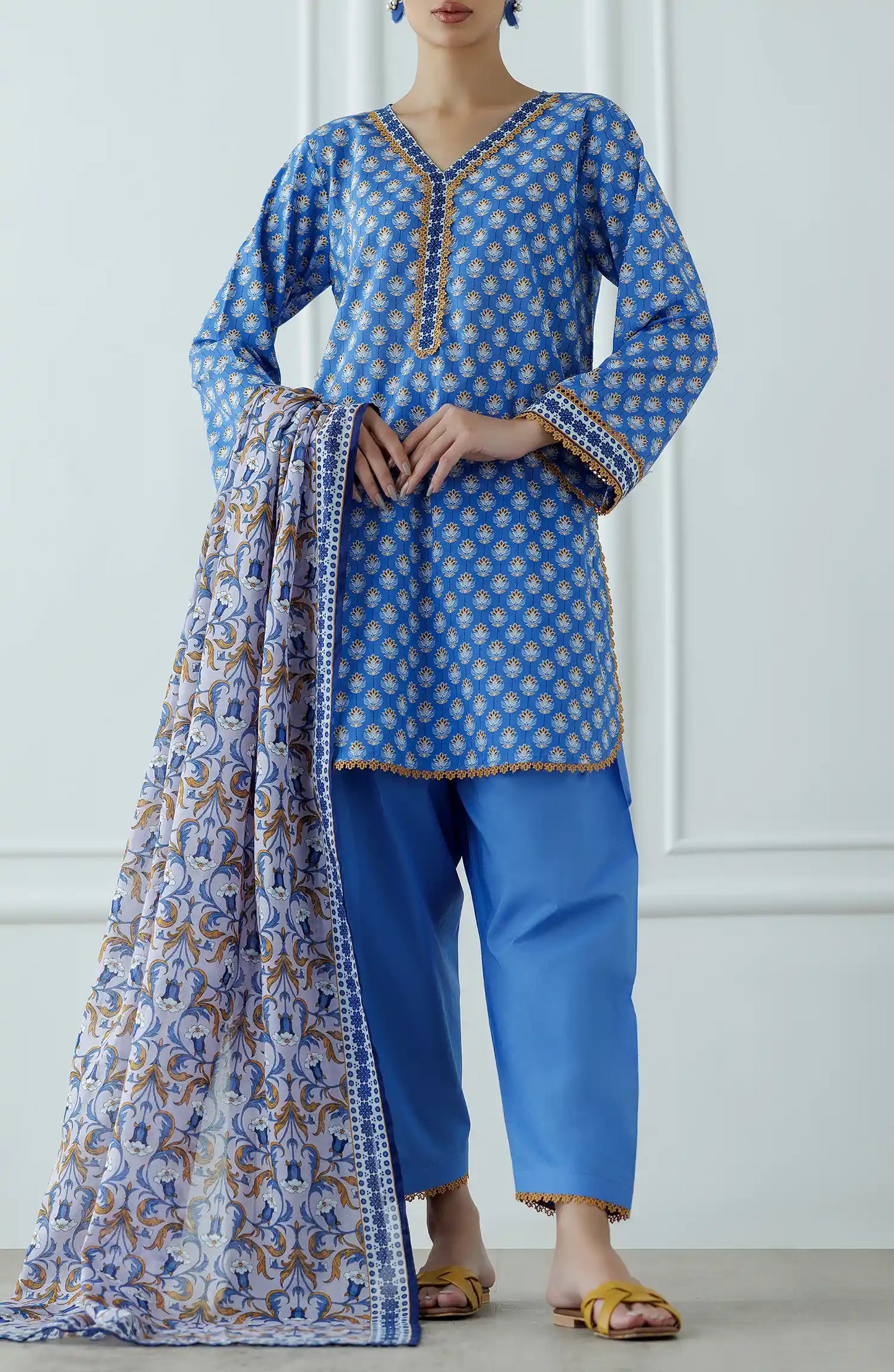 Woman wearing a blue and white patterned kurta with matching pants and a floral dupatta on a dyed traditional shalwar. Stitched Printed Lawn Shirt Dupatta & Pant - 3 Piece - OTL-25-061.