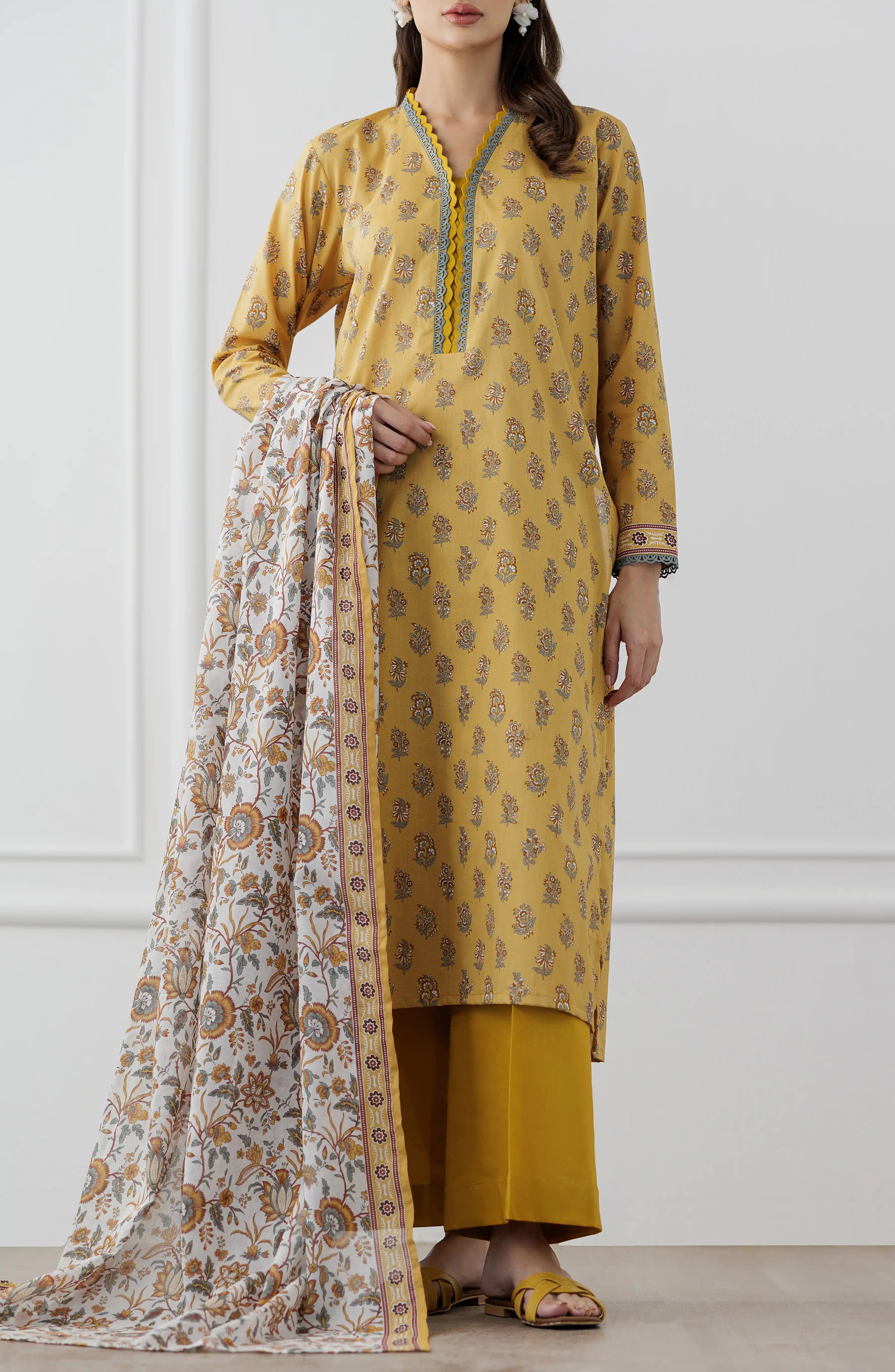 Woman wearing a mustard yellow kurta with a floral dupatta against a dyed trouser. Unstitched Printed Lawn Shirt Dupatta & Pant - 3 Piece Suits - OTL-25-118