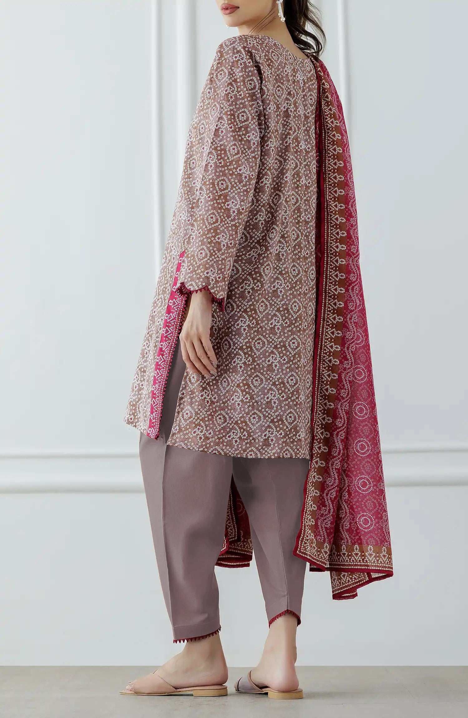 Woman wearing a patterned kurta with pants and a pink dupatta against a dyed trouser. Stitched Printed Lawn Shirt Dupatta & Pant - 3 Piece - OTL-25-308. 