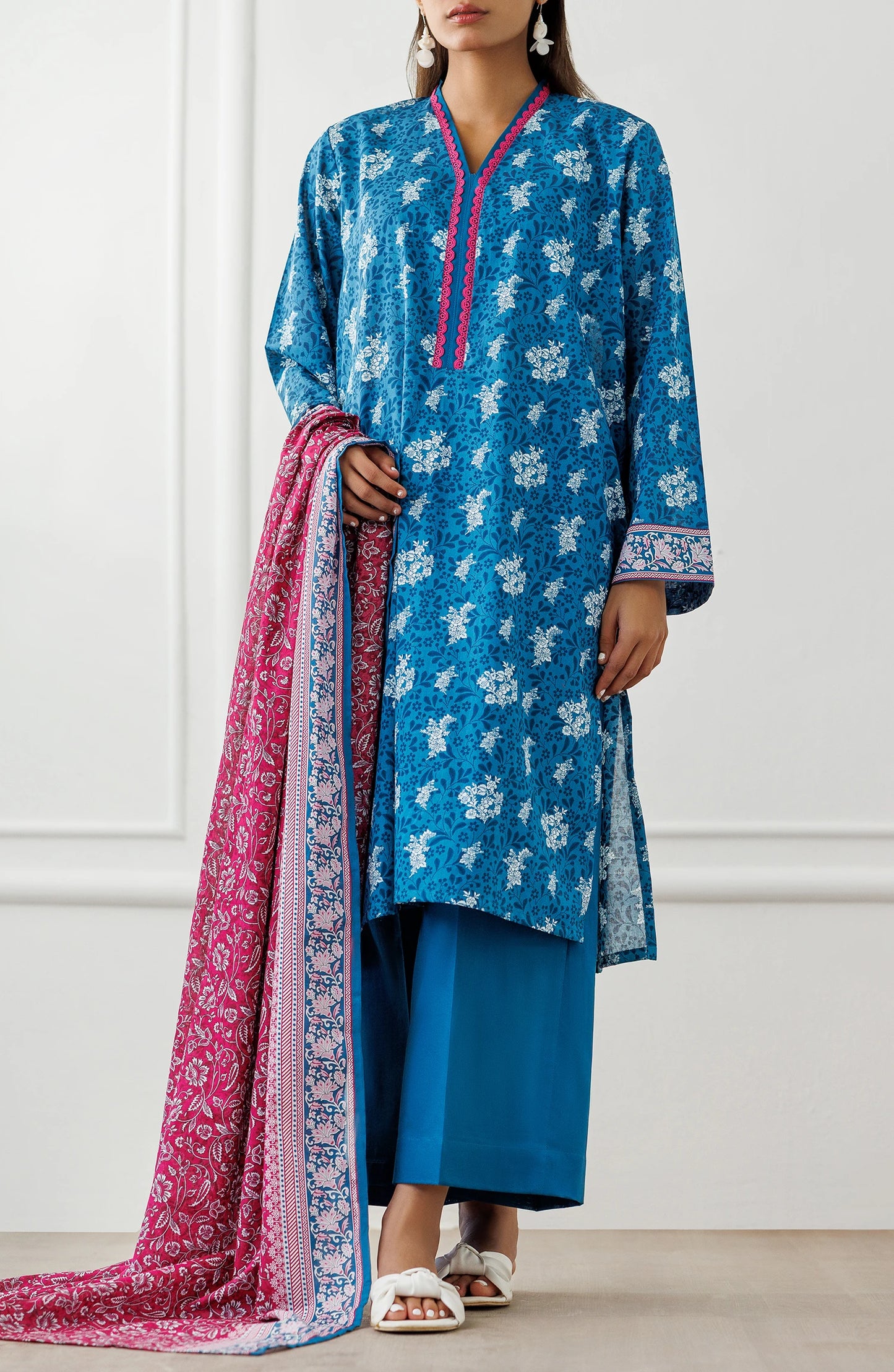 Woman wearing a blue floral dress with a pink dupatta against a matching trouser. Unstitched Printed Lawn Shirt Dupatta & Pant - 3 Piece Suits - OTL-25-477