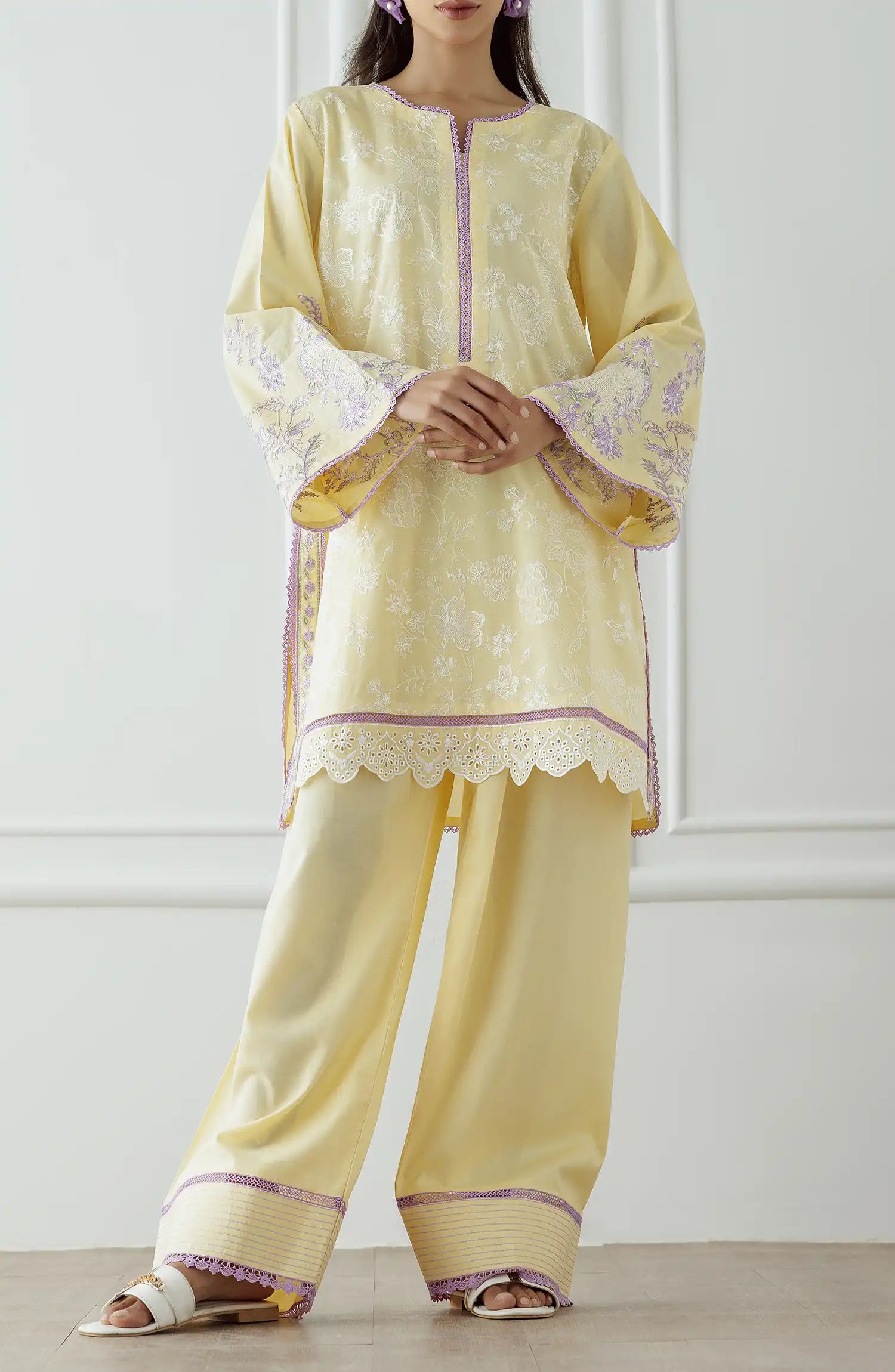 Stitched Embroidered Lawn Shirt & Pant - 2 Piece (Co-ord Set) - WRCJ25S-2001. Woman wearing a light yellow traditional outfit with purple accents against dyed farshi shalwar.