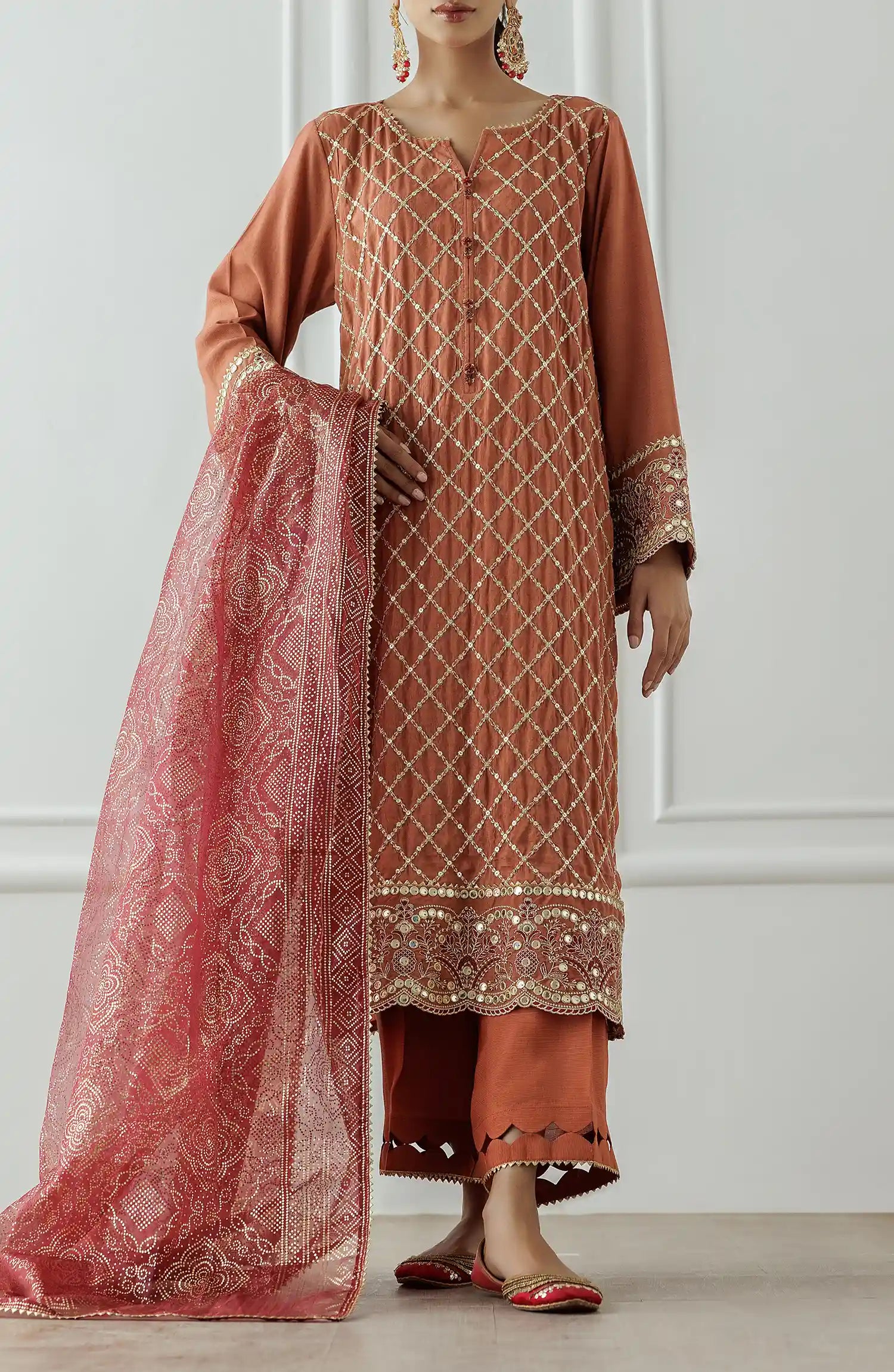 Woman wearing a traditional outfit with a rust-colored kurta and pants, holding a matching dupatta. Stitched Luxury Festive Formal Raw Silk Shirt Dupatta & Pant - 3 Piece Suits - WRFR24W-3004