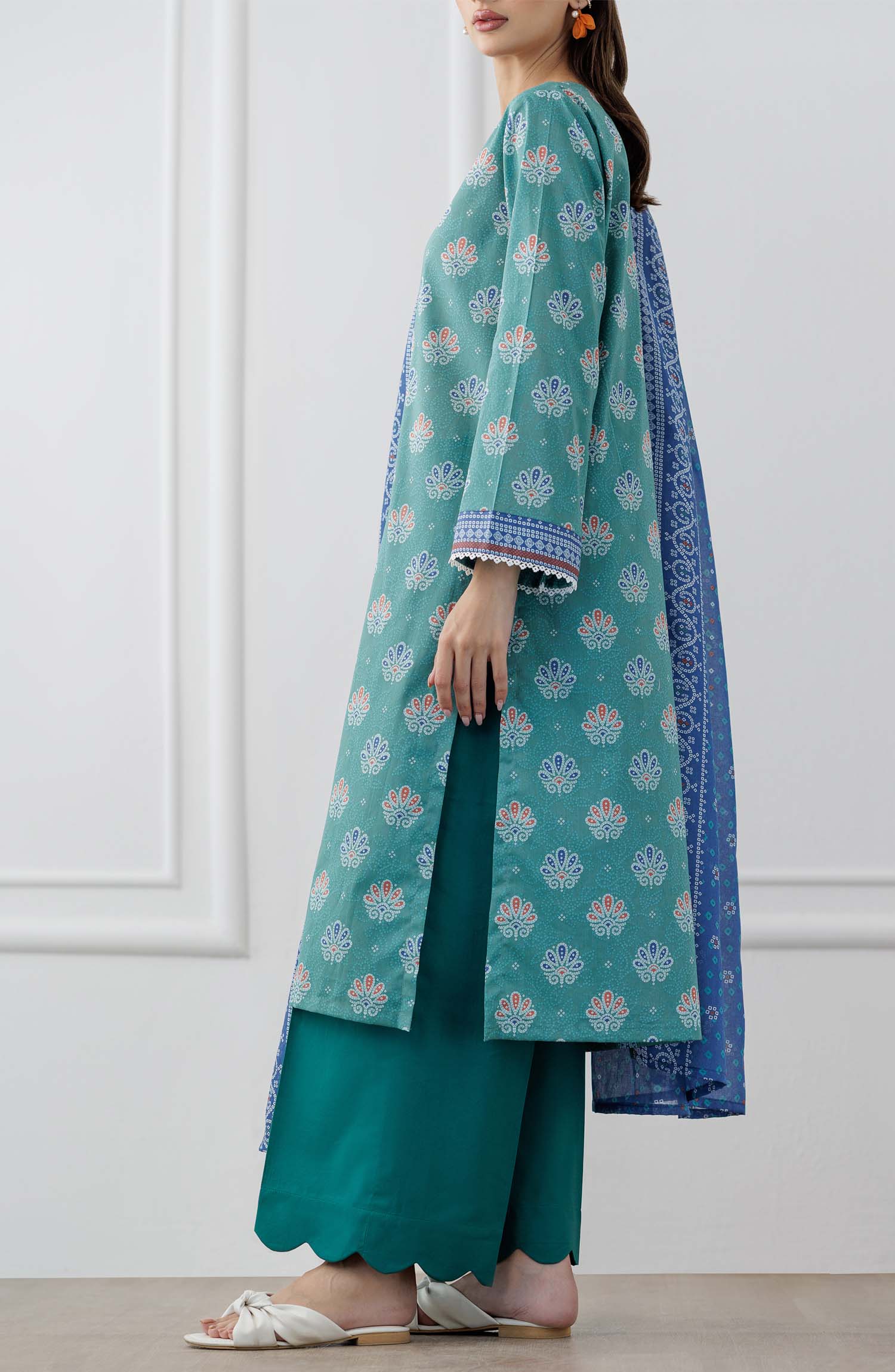 UNSTITCHED Printed Lawn Shirt Dupatta & Pant - 3 Piece Suits - OTL-25-307. Woman wearing a teal traditional outfit with a blue dupatta against a dyed trouser.